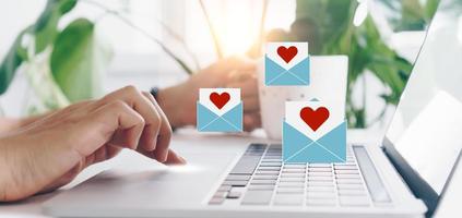 mão digitando teclado com laptop com mídia social carta de amor enviar ícones do dia dos namorados. foto