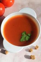 vertical ainda vida a partir de uma prato com tomate sopa, tomates e Migalhas de pão foto