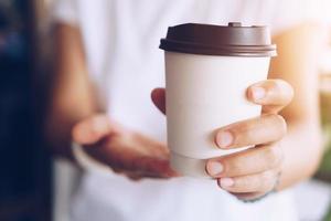 mão segurando uma xícara de café com reflexo de luz solar foto