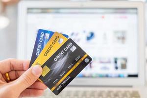 mãos segurando um cartão de crédito e usando um laptop, conceito de compras online foto