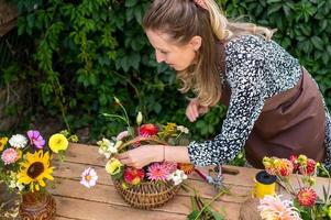 uma florista menina coleta uma ramalhete do outono flores dentro uma cesta foto