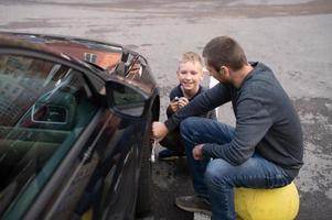 fofa Garoto ajuda Papai consertar a carro. desparafusar a roda foto