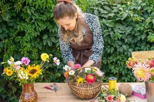 uma florista menina coleta uma ramalhete do outono flores dentro uma cesta foto