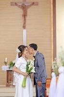 noiva e noivo tocante narizes depois de Casamento votos com Cruz fundo dentro a igreja, Novo viagem tem começasse foto