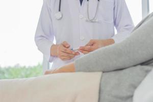 a médico é examinando a paciente dentro a hospital. caucasiano médico vestindo vestido e estetoscópio mostrando termômetro para fêmea paciente às hospital. foto