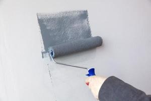 fechar-se tiro do do pintor mão dentro branco luva pintura uma parede com pintura rolo foto