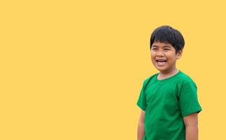 o menino vestia uma camisa verde e sorria. em um fundo amarelo foto