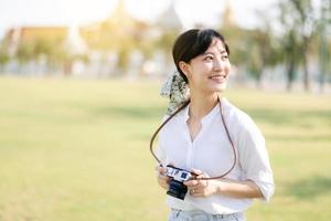 retrato do ásia mulher viajante usando Câmera. Ásia verão turismo período de férias conceito com a grande Palácio dentro uma fundo às Bangkok, Tailândia foto