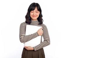 lindo jovem ásia mulher em suéter roupas segurando computador portátil pc computador e olhando às Câmera com sorrir face, isolado em branco fundo foto