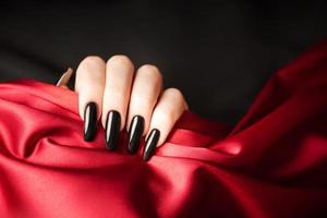 mãos de uma jovem com manicure preta nas unhas foto