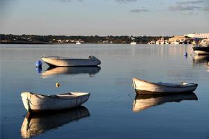 três pequeno barco em a costa às pôr do sol foto