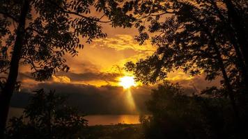 dourado hora pôr do sol panorama com lago Visão geral e silhueta do árvores foto