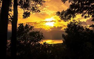 dourado hora pôr do sol panorama com lago Visão geral e silhueta do árvores foto