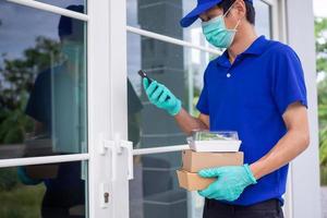 a masculino Entrega funcionários em pé às a porta desgasta uma uniforme com uma mascarar e luvas entregar Comida de acordo com para ordens este clientes ligar para ordem. serviço conectados ordem Comida conceito. foto