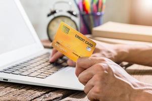pessoa que usa um cartão de crédito para fazer compras online através do computador foto