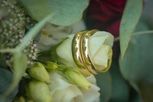 anéis de casamento em um buquê de flores brancas foto