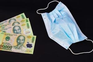 máscara facial com dinheiro vietnamita em fundo preto foto