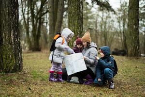 mãe e crianças com mapa dentro a floresta. foto