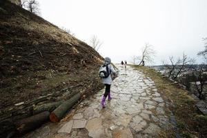 mãe e meninas andar acima a molhado caminho para a antigo medieval castelo fortaleza dentro chuva. foto