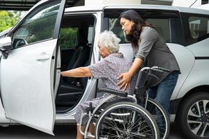 cuidador Socorro e Apoio, suporte ásia idosos mulher sentado em cadeira de rodas preparar pegue para dela carro para viagem dentro feriado. foto