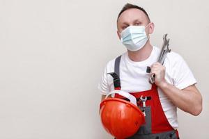 retrato engenheiro trabalhador ou mecânico vestindo capacete e face mascarar para proteger vírus cobiçado 19 em branco fundo, com segurando chave inglesa. trabalho dia foto