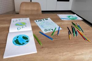 crianças desenhos do a planeta terra com uma mundo mapa com multicolorido lápis em branco papel mentira em a cozinha mesa às lar. a conceito do a dia do Paz e terra foto