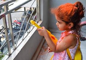 doce pequeno indiano menina jogando cores em holi festival, segurando pichakaree cheio do cores, holi festival celebrações dentro Délhi, Índia foto