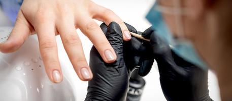 manicuro remove cutículas em fêmea unhas foto