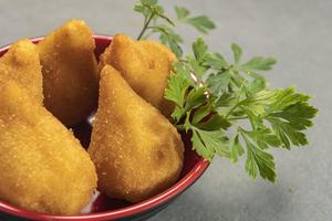 tradicional frito coxinha dentro prato em ardósia fundo, popular brasileiro lanche foto