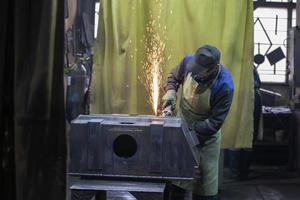 uma soldador trabalho com metal dentro uma fábrica fazer compras. foto