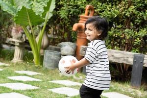 fofa pequeno Garoto jogando futebol com bola ao ar livre em futebol campo foto