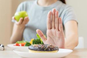 dieta, dieta ásia jovem mulher ou menina usar mão empurrar fora, negar doce rosquinha e escolher verde salada vegetais, comer Comida para Boa saudável, saúde quando com fome. fechar acima fêmea peso perda pessoa. foto