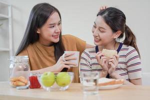 feliz lésbica, prazer ásia jovem dois mulheres, menina gay ou fechar amigo, casal amor , momento gastos Boa Tempo junto, tendo encontro comendo café da manhã em mesa às lar. atividade do lazer, relaxar. foto