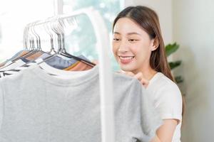 escolha do roupas, nada para vestir. atraente ásia jovem mulher, menina experimentar em aparecer, feliz escolhendo vestir, equipamento em cabide dentro guarda roupa dentro quarto armário de roupa às lar. decidir blusa o que para colocar em que 1 foto