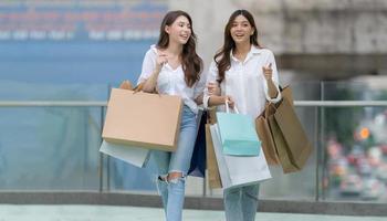 feliz amigos compras, dois jovem fêmea estão segurando compras bolsas foto