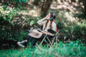 jovem mulher asiática sentada na cadeira ouvindo música do fone de ouvido foto