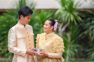 jovem casal segurando uma tigela de água no festival songkran foto