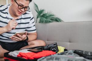 homem asiático está preparando roupas em malas foto