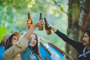 jovem torce e bebe bebida na frente da barraca de acampamento foto