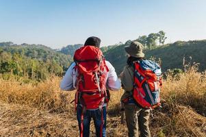 viajante casal com mochila em pé olhando Visão em montanha foto