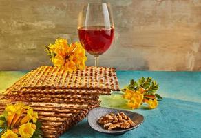 pesach celebração conceito - judaico feriado pesach. fundo com amarelo flores com vidro do vinho, matzah e prato do seder dentro a raios do a Sol. tradicional judaico inscrições em prato foto