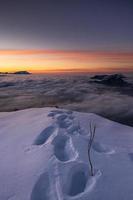 inverno panorama em topo do uma montanha durante uma pôr do sol com sapato impressões dentro neve foto