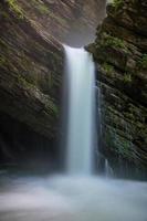 uma místico cascata fluindo a partir de uma caverna foto