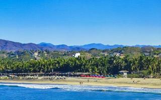 Sol de praia falésias pedras ondas Palmeiras montanhas porto escondido México. foto