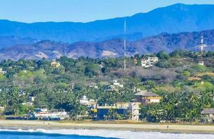 Sol de praia falésias pedras ondas Palmeiras montanhas porto escondido México. foto