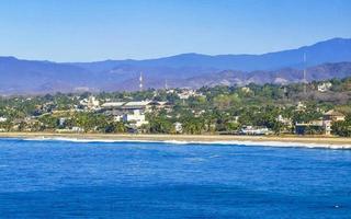 Sol de praia falésias pedras ondas Palmeiras montanhas porto escondido México. foto