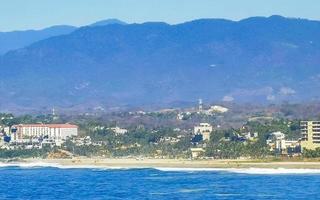 Sol de praia falésias pedras ondas Palmeiras montanhas porto escondido México. foto