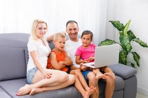 lindo sorridente multético família dentro frente do a computador portátil vídeo ligar com distante pais às lar. foto