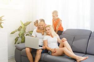 feliz família às casa usando uma computador portátil foto
