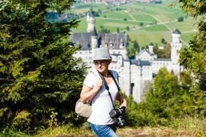 jovem mulher com famoso real castelo Neuschwanstein em fundo. feliz inverno final de semana dentro a interior. período de férias dentro montanhas. Alpes, baviera, Alemanha foto